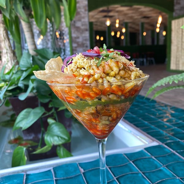 A Bombay Spice II Bhel Puri in a martini glass with a restaurant interior background.