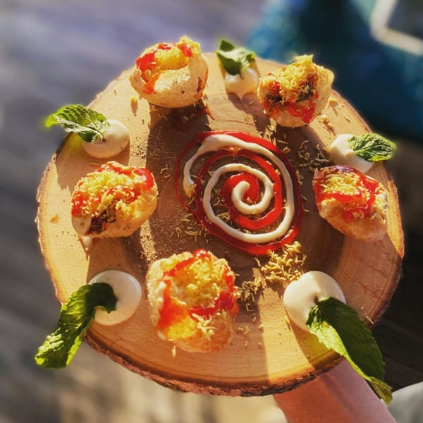 Indian pani puri appetizers with sauces and mint on a rustic wooden board.